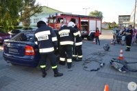Strażacy robią pokaz ratowniczy w którym ratują osoby z samochodu osobowego.